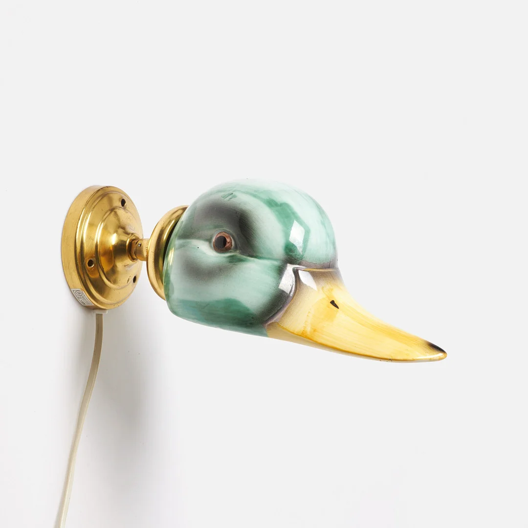 VÄGGLAMPA, i form av and, porslin, mässing, Gamla Stans Lampverkstad, porslin samt gulmetall, etikettmärkning, typ 1694. — Wall Lights — Stockholms Auktionsverk Sickla