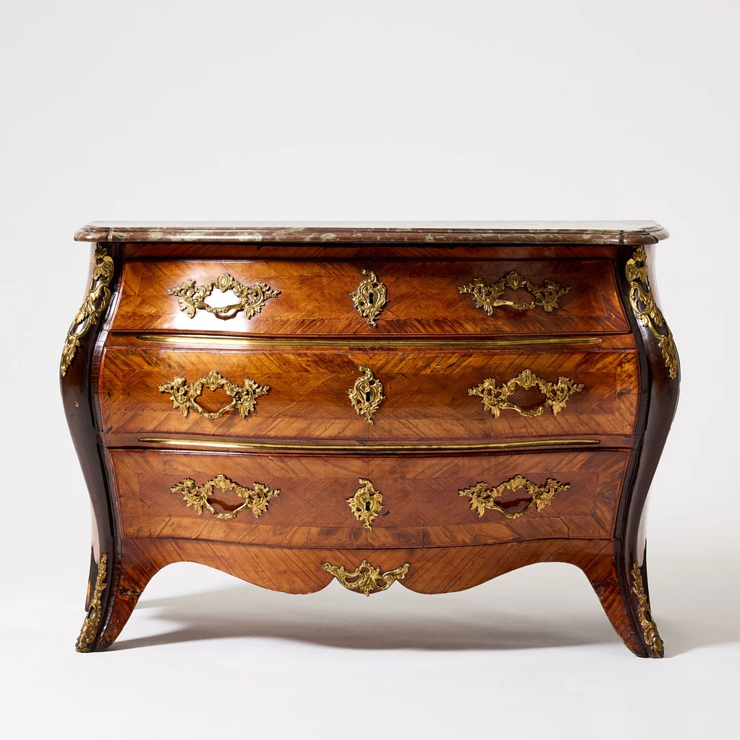 BYRÅ, 1700-tal, Stockholmsarbete i rokoko, profilerad skiva, fanérad i bl a mahogny, valnöt, och rot, förgyllda beslag. — Chests of drawers — Stockholms Auktionsverk Magasin 5