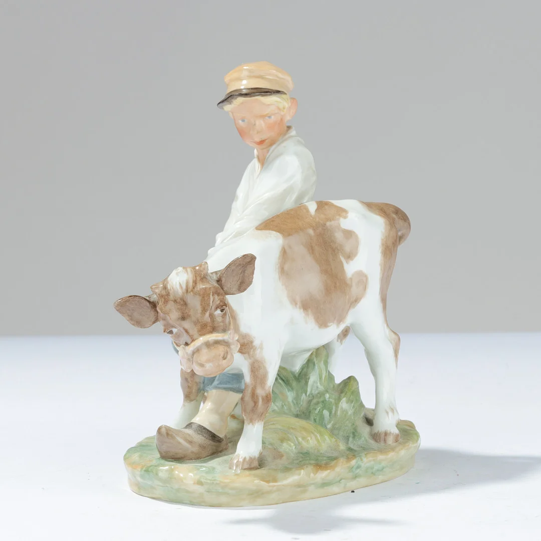ROYAL COPENHAGEN. 'Dreng med kalv' Figur af porcelæn dekoreret med overglasur. Juliane Marie mærke.Danmark. — European — Palsgaard Kunstauktioner