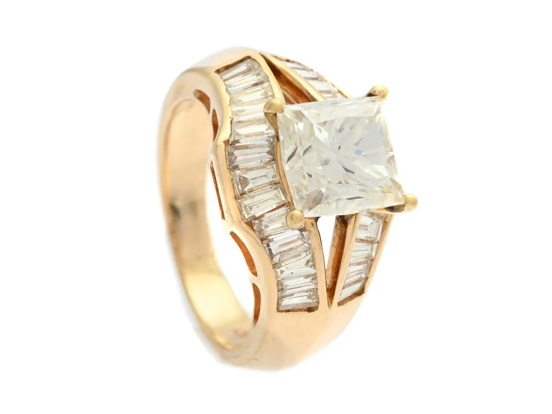 RING, 14K guld, octagonalt modifierad prinsesslipad diamant 2,44 ct, W(H)/VVS2, 26 trapetsslipade diamanter ca 0,75 ctv, TW-TCr/VS, stl 16,25 mm, vikt 6,6 g, mittstenen sitter något löst i sin fattning. — Smycken/Ring — Kaplans