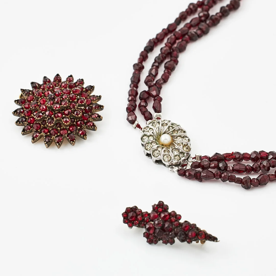 BROSCHER, 2 st., COLLIER, 3-radigt, fasettslipade granater, delvis äldre granater. — Necklace — Stockholms Auktionsverk Magasin 5