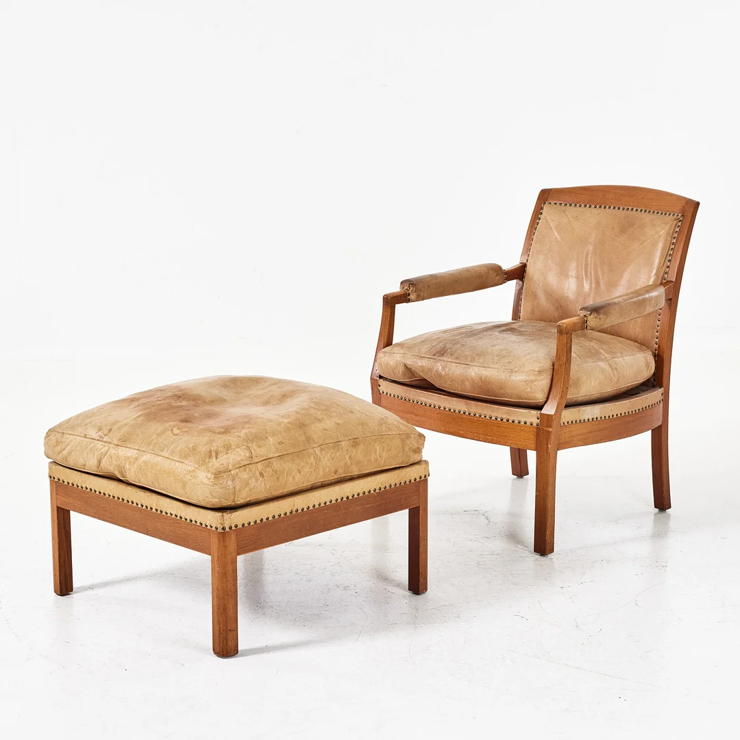 KERSTIN HÖRLIN-HOLMQUIST. "Famnen", fåtölj med fotpall, Triva-serien, Nordiska Kompaniet, 1960-tal, mahogny, pärlspikad klädsel i ljust läder. — Armchairs & Chairs — Stockholms Auktionsverk Magasin 5