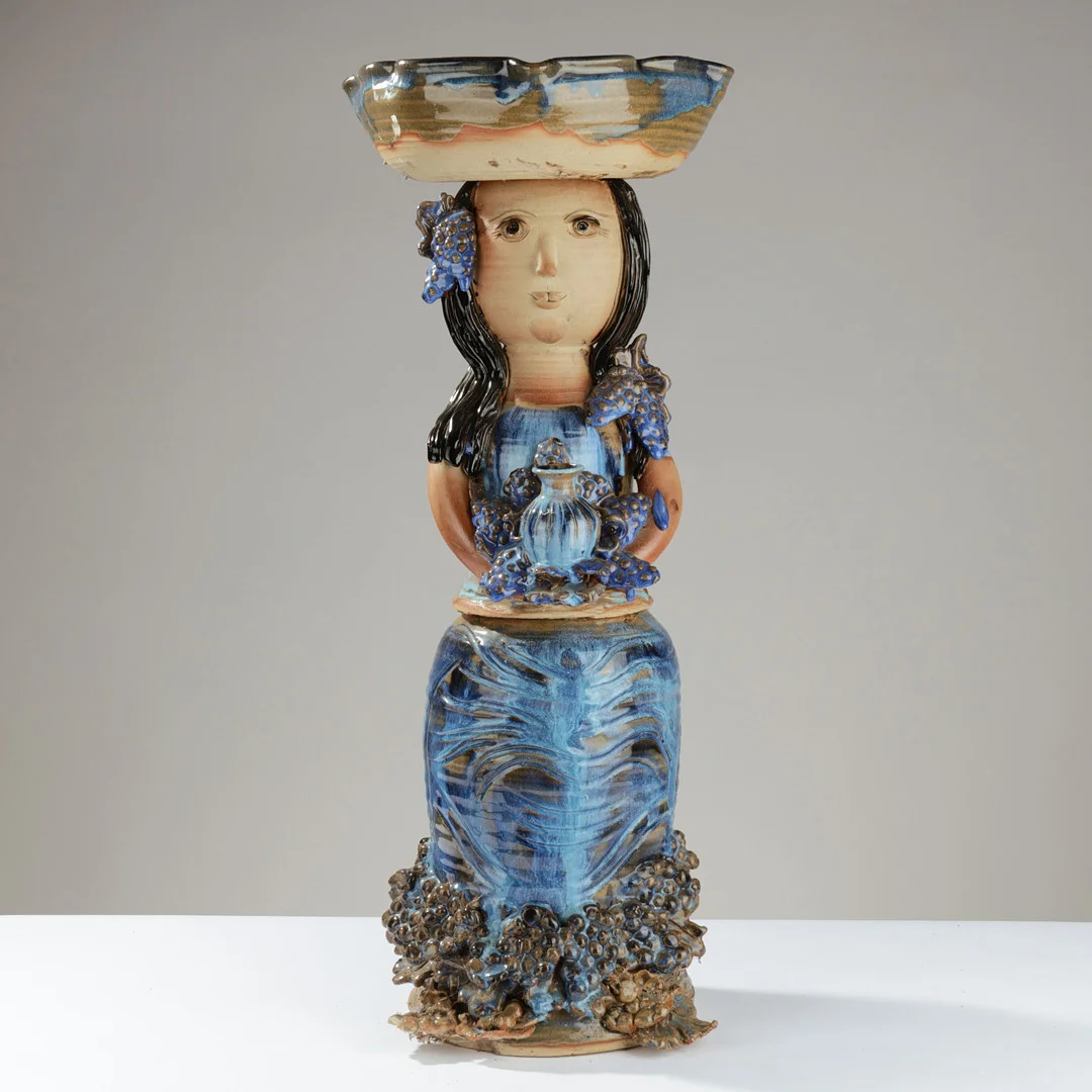 KIRSTEN CLEMANN (1932–2014). Stor skulptur forestillende kvinde med vase og vindrueklaser, håndlavet af keramik glaseret i overvejende blå nuancer, udført på eget værksted i Østermarie på Bornholm, Danmark, 1900-tallets anden halvdel. — Sculptures & Bronzes — Palsgaard Kunstauktioner