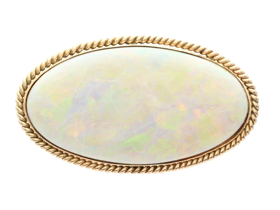 BROSCH, ca 12K guld, nål i 18K guld, cabochonslipad opal ca 40,00 ct, mått 52x30 mm, vikt 20,7 g, opalen har ytlig sprickbildning. — Smycken/Brosch — Kaplans