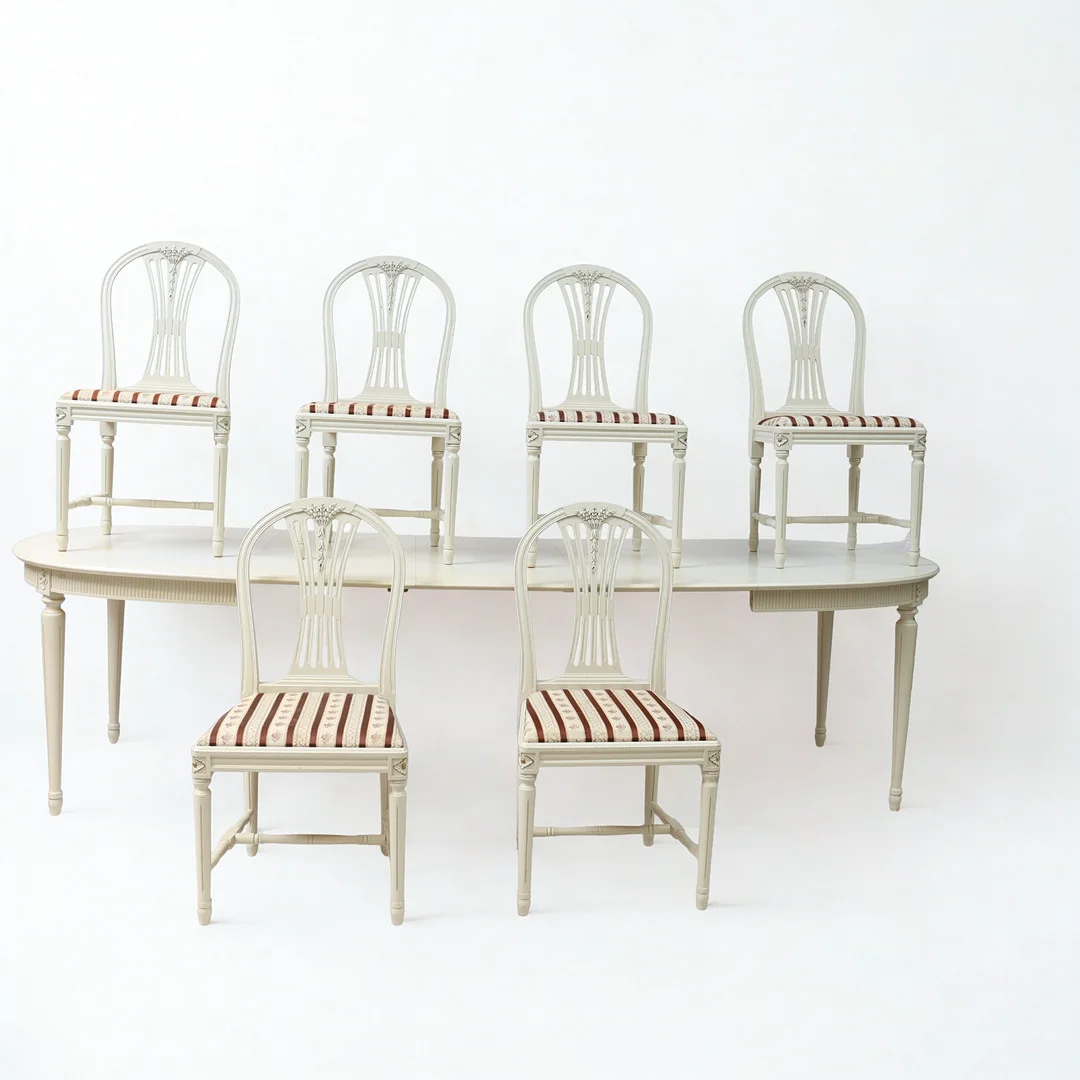 MATSALSMÖBLEMANG, 6st stolar samt matbord med 3 iläggsskivor, Gustaviansk stil, 1900-tal, vitmålat med bronserad dekor, genombruten ryggbricka. — Dining room furniture — Falun Auktionsbyrå