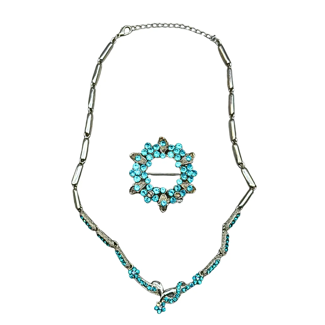 SCHMUCKSET - GLIEDERKETTE UND BROSCHE MIT TÜRKISFARBENEN STRASSSTEINEN. — Jewellery — Auktionshaus Stuber's Hammerschlag
