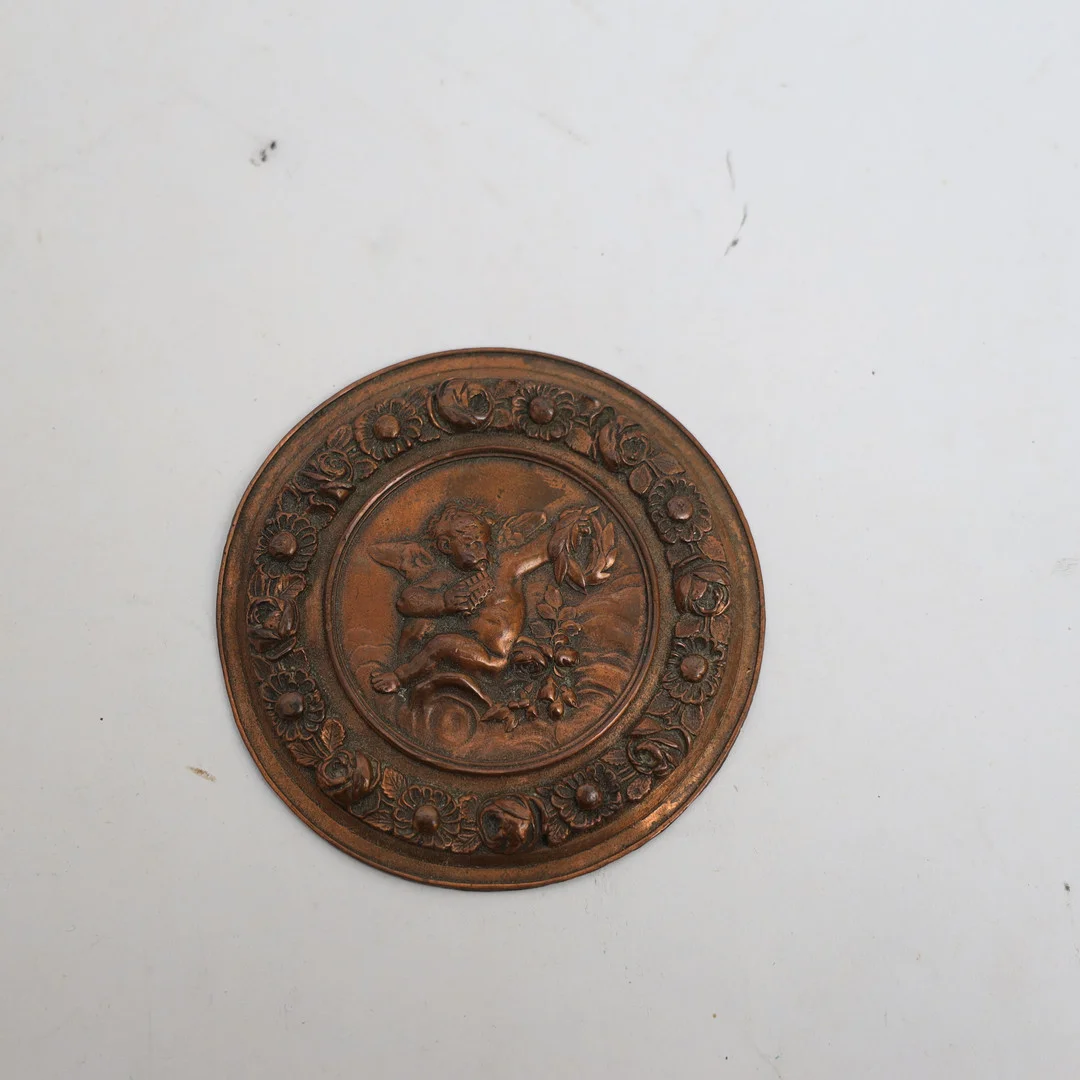 DEKORATION, 1800-1900-tal, förkoppad metall, med rik reliefdekor av bland annat kerub. — Other metals — Falun Auktionsbyrå