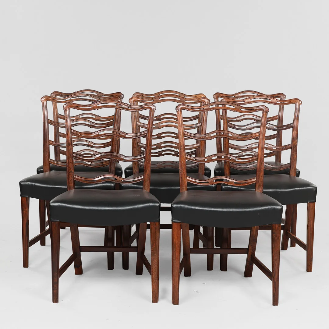 A.J. IVERSEN. TILSKREVET. Sæt på otte 'Ladderback' stole af palisander og sort læder, 1950-60'erne, Danmark. (8). — Armchairs & Chairs — Palsgaard Kunstauktioner