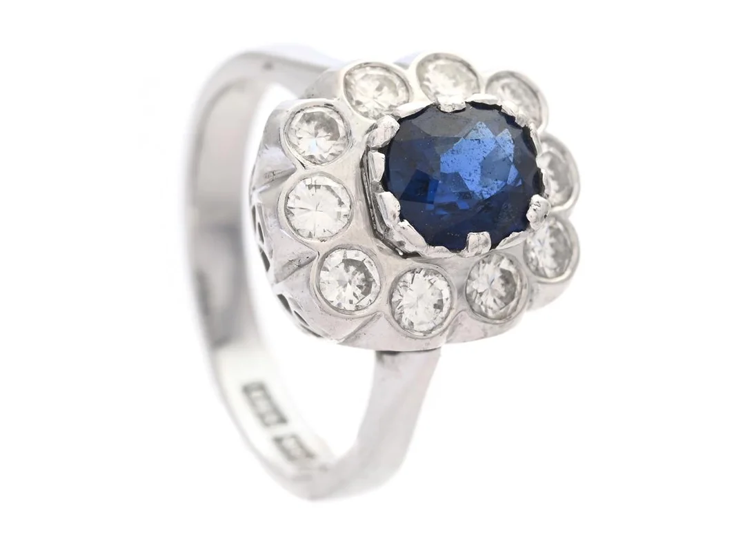 CARMOSÉRING, 18K vitguld, ovalslipad safir 0,79 ct enligt gravyr, 10 briljantslipade diamanter ca 0,67 ctv, ca TW-W(G-H)/VS, Bengt Andersson, Stockholm 1980, stl 15,5 mm, vikt 4,8 g — Smycken/Carmoséring — Kaplans