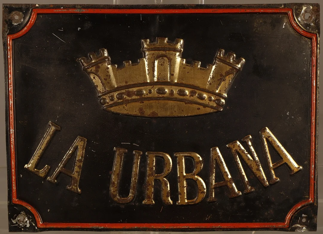 La Urbana, placa publicitaria en hojalata estampada y pintada. — Other collectables — Barcelona Auctions