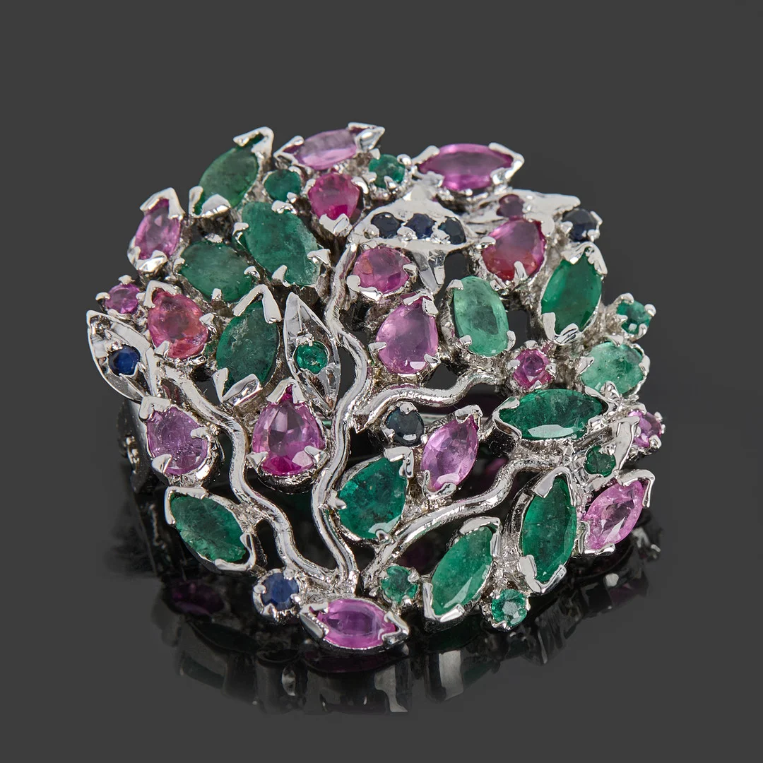 BROSCH/HÄNGE, vitmetall, genombruten dekor dekorarat med smaragder, safirer samt rubiner. — Brooches & Pendants — Crafoord Auktioner Stockholm