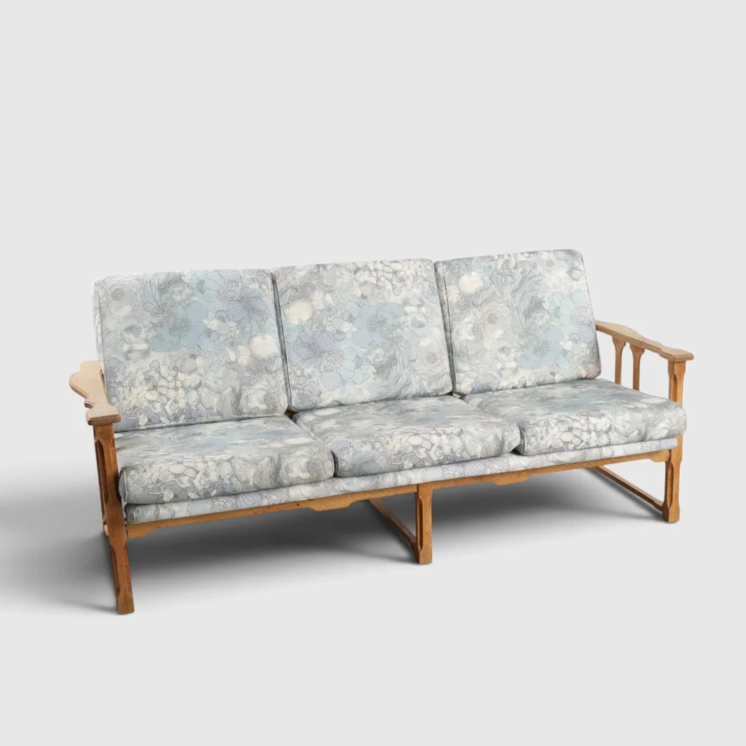 DANSK MØBELDESIGN. 3 pers. sofa af eg, med hynder i blomstret stof. Henry Kjærnulf-stil, dekorative detaljer ved armlæn. 1960-70'erne. Danmark. — Coffee Tables — Woxholt Auktionshus