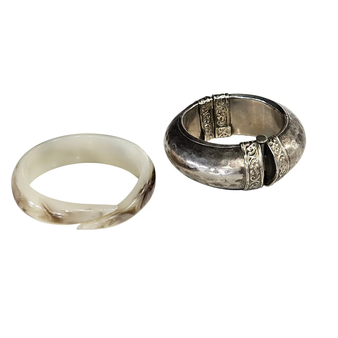 Dos pulseras tipo esclava en metal y resina. — Costume Jewellery — Arce Auctions