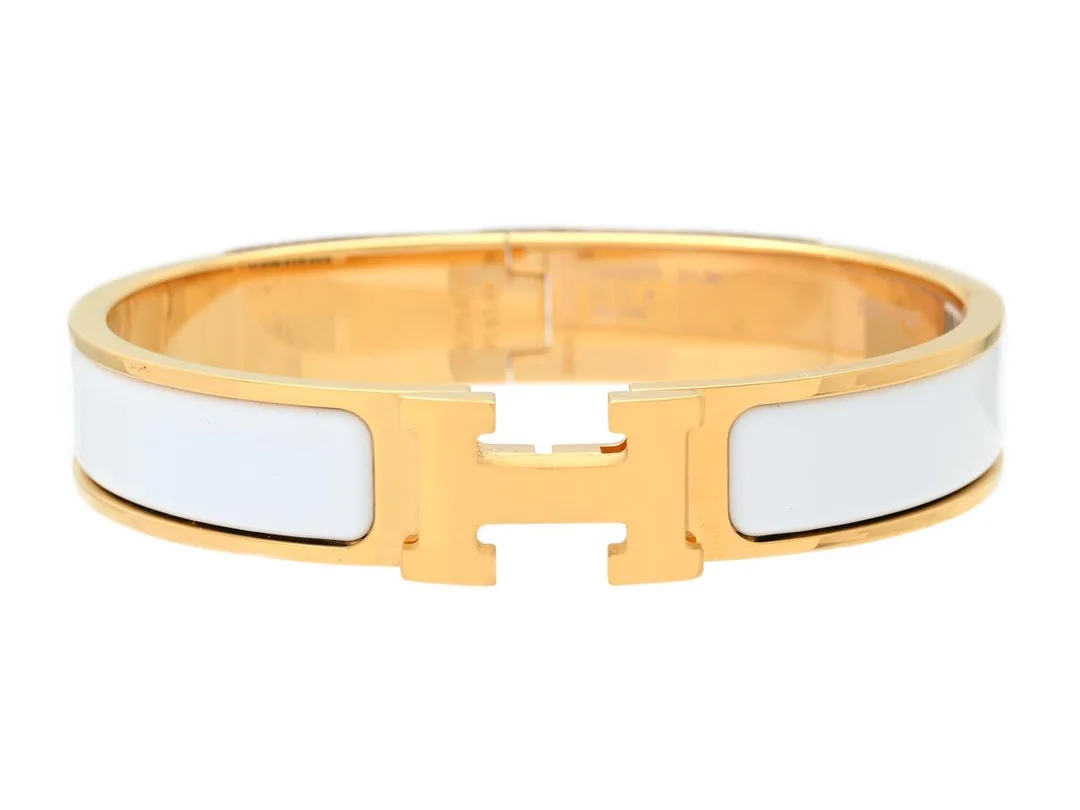 HERMÈS, ARMRING, Clic Clac H Bracelet, vit emalj, guldfärgade beslag, bredd 1 cm, diameter 5,5 cm, smyckespåse, originalask, plast kvar på beslag. Very Good Condition. — Smycken/Armring — Kaplans