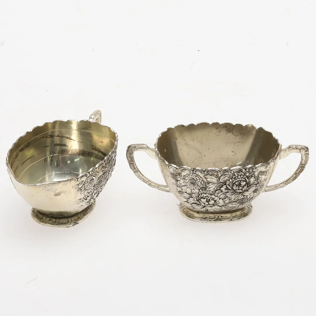 SOCKERSKÅL och GRÄDDKANNA, Vitmetall med reliefdekor av blomster, Stämplad T.K, 1900-talets andra halva. — Other metals — Örebro Stadsauktioner