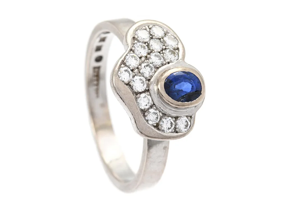 CLAES GIERTTA, ring, 18K vitguld, ovalslipad safir, briljantslipade diamanter ca 0,30 ctv, ca VS/TW-W, Stockholm 1992, stl 19,5 mm, vikt 7,6 g, skador på safiren, svaga fattningar, sliten skena. (d) — Smycken/Ring — Kaplans