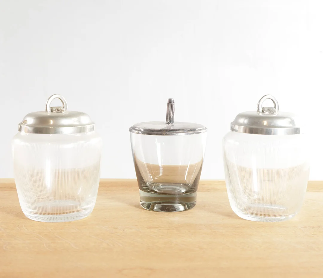 PER LÜTKEN / JUST ANDERSEN. Tre krukker af klart glas med låg af tin og sølvplet. Udført hos bl.a. Holmegaard, Danmark (3). — Art glass — Woxholt Auktionshus