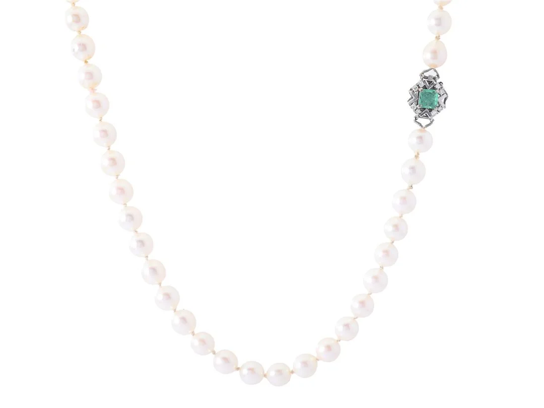 PÄRLCOLLIER, odlade pärlor, ca 6,8-6,9 mm, lås i 18K vitguld, smaragd ca 0,45 ct enligt gravyr, 4 åttkantslipade diamanter ca 0,09 ctv enligt gravyr, längd 48 cm, vikt 29,6 g. skört silke, skadade stenar. — Smycken/Pärlcollier — Kaplans