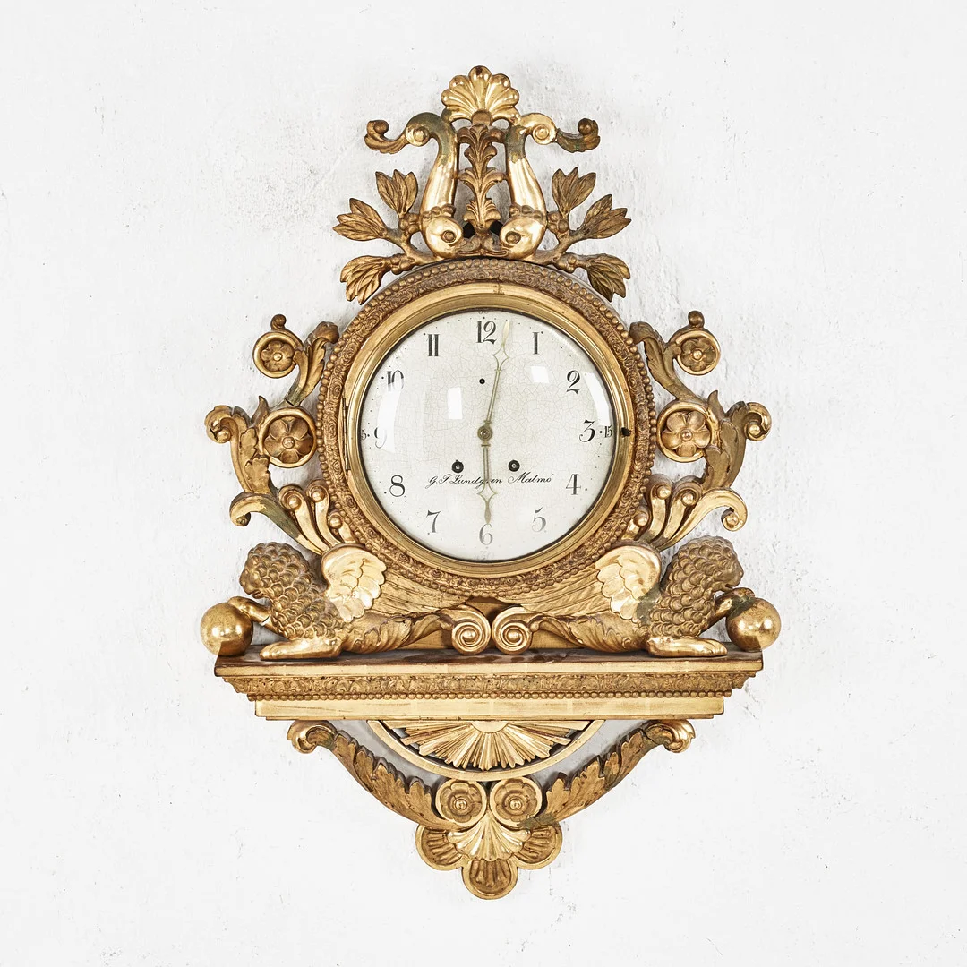 VÄGGPENDYL, senempire, 1800-talets andra kvartal, urtavlan märkt G.T. Lundgren Malmö (Georg Tyko L. 1805-1875, urmakare i Malmö), träskuren dekor och pastellage, förgyllt och bronserat. — Wall Clocks — Stockholms Auktionsverk Magasin 5