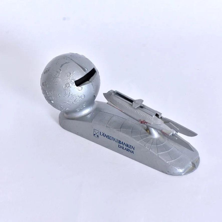 SPARBÖSSA, rymdraket och månen, Länssparbanken Dalarna. — Other collectables — Halmstads Auktionskammare