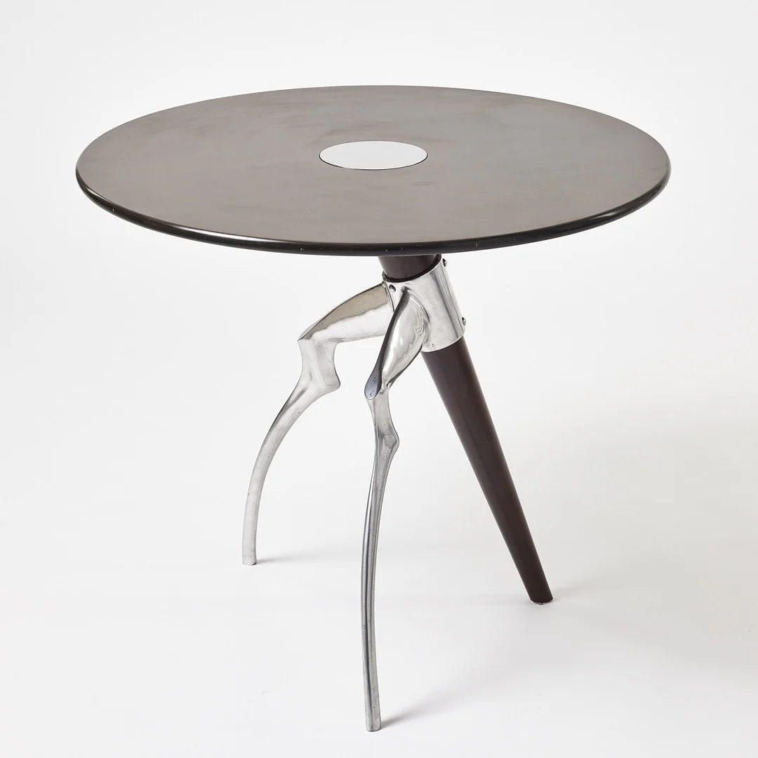 MATTHEW HILTON. "Antilope" , bord, London 1980-tal, rund skiva, två animaliskt formade ben i polerat aluminium, ett ben i brunbetsat trä. — Tables — Stockholms Auktionsverk Magasin 5