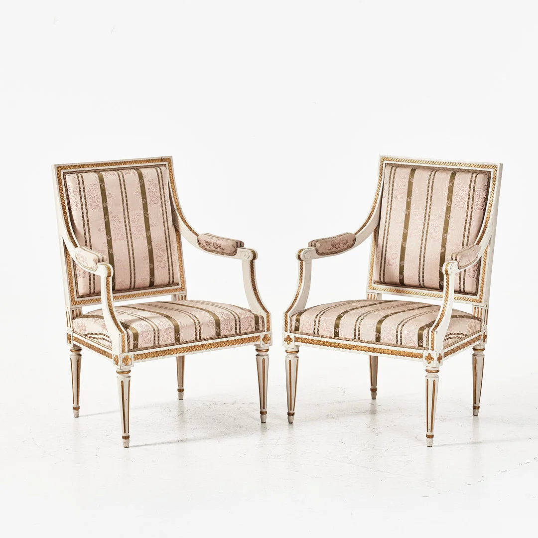 FÅTÖLJER, 2 st., varav en gustavianskt stockholmsarbete, en senare kopia 1900-talets början, skuren dekor, bemålade i vitt och guld. — Armchairs & Chairs — Stockholms Auktionsverk Magasin 5