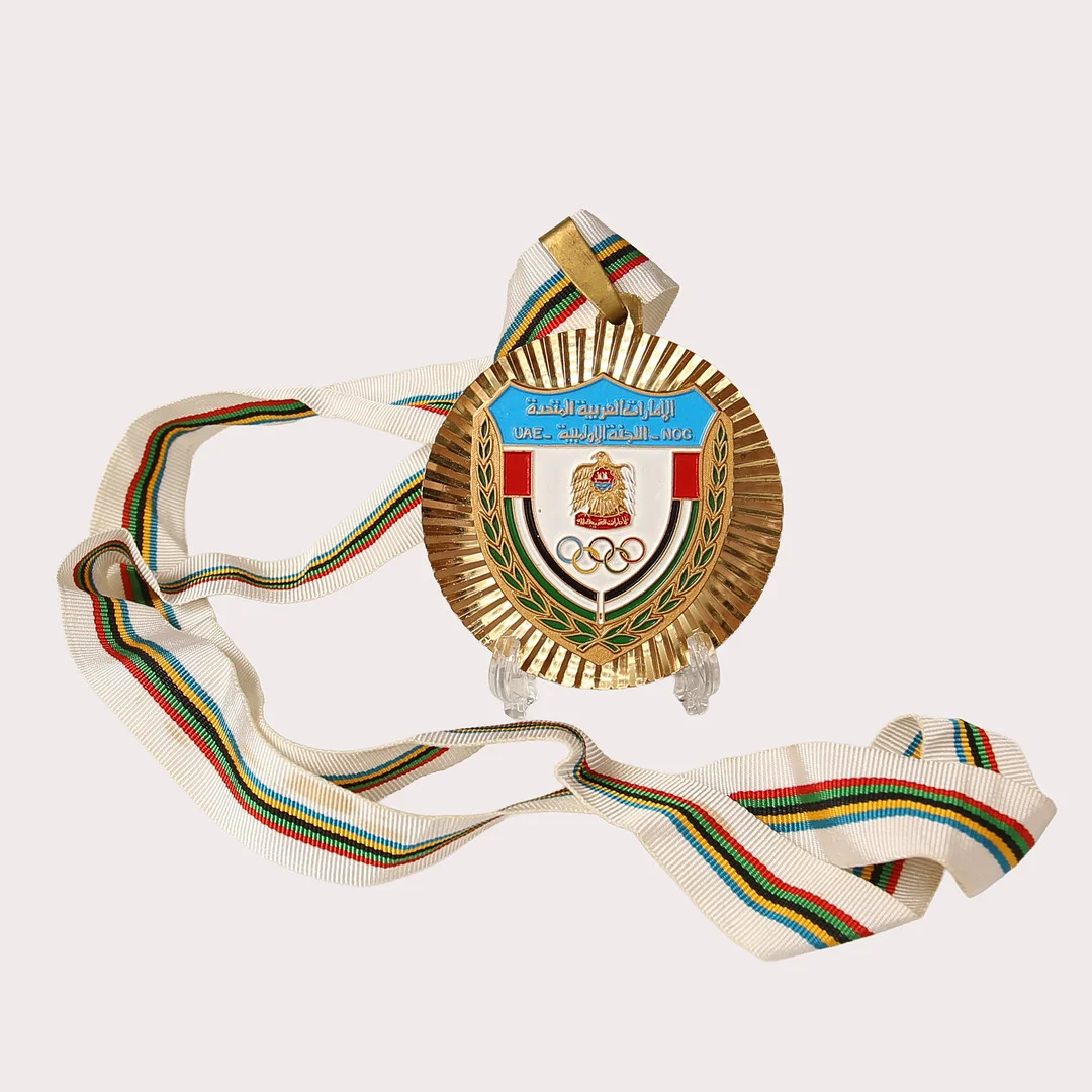 OLYMPISK MEDALJ , förgylld metall. Förenade Arabemiraten, 1988-1991. — Orders & Medals — Limhamns Auktionsbyrå