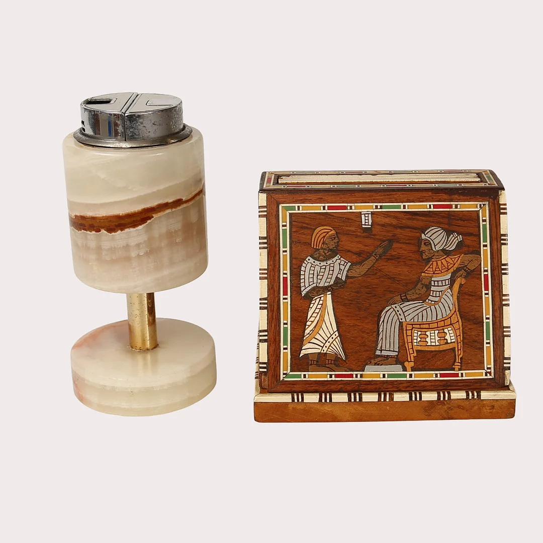 CIGARRETTSTÄLL, trä med polykroma inläggningar, i fornegyptisk stil. Samt BORDSTÄNDARE, onyx och metall, 1900-talets tredje fjärdedel. — Miscellaneous — Limhamns Auktionsbyrå