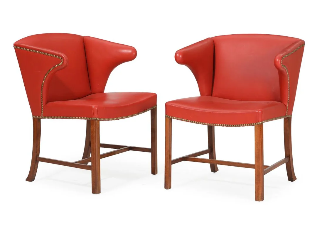 A pair of armchairs with dark stained beech legs. Seat, back and armrests upholstered with red leather, fitted with brass nails. Designed 1933. Made by cabinetmaker Frits Henningsen. 1940s. (2) — Modern Furniture — Bruun Rasmussen