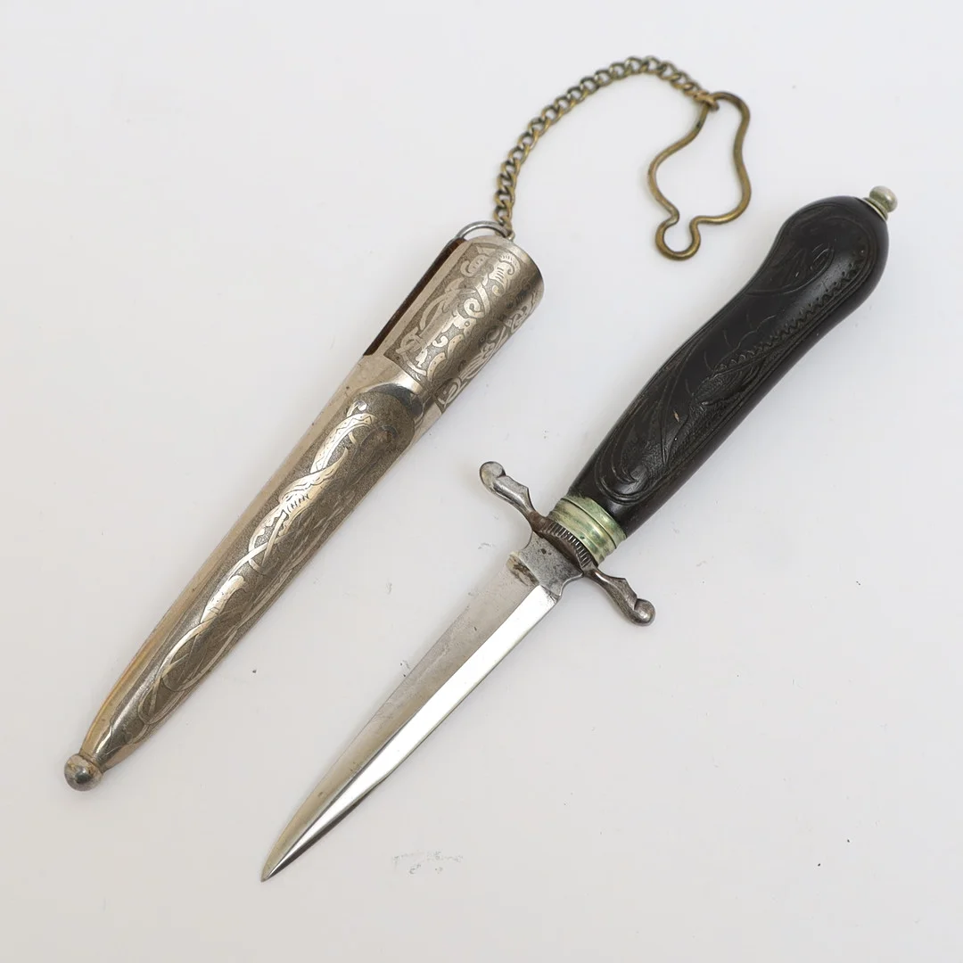 CW DAHLGREN. Kniv med slida, Eskilstuna, handtag med skuren dekor av drake. blad av stål, slida med etsad dekor. Stämplade. — Edged weapons — Falun Auktionsbyrå