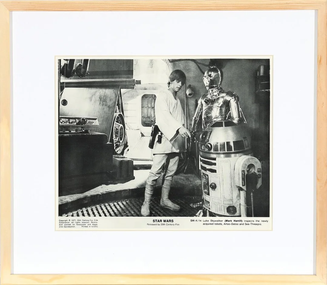 ‘Star Wars’. Luke Skywalker (Mark Hamill, b. 1951) examines the newly acquired R2-D2 and C-3PO. Visible size 19 × 25 cm. Frame size 31 × 37 cm. — Photos/Vintage photographs — Bruun Rasmussen