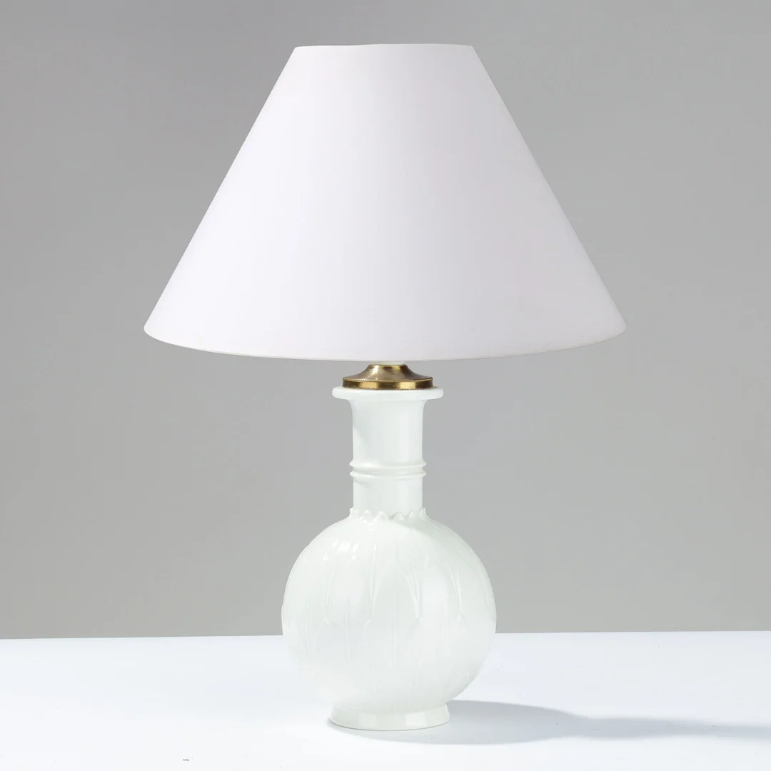 ARNO MALINOWSKI (1899-1976). Bordlampe dekoreret med stiliserede blade i relief, nordisk Art Deco stil, fremstillet af Blanc de Chine porcelæn med messinghætte, modelnr. 3309, Royal Copenhagen, Danmark, udført i 1936. — Table Lamps — Palsgaard Kunstauktioner