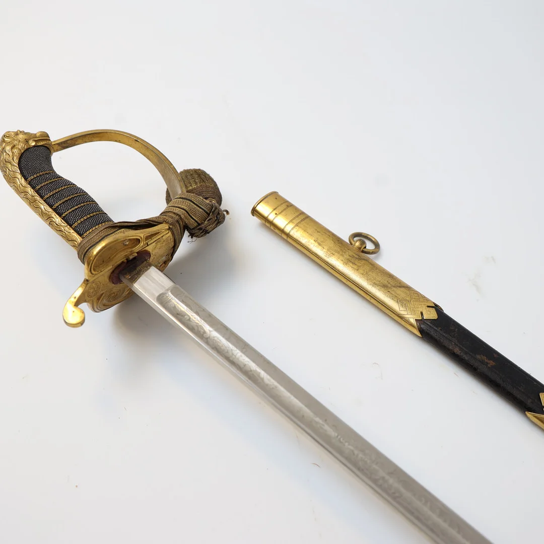 SJÖOFFICERSSABEL, Kungliga Flottan Model 1878/1915, Klinga med etsad dekor, parerskydd av mässing med dekor av lejon och svenska flottan. Med portepe. — Edged weapons — Falun Auktionsbyrå