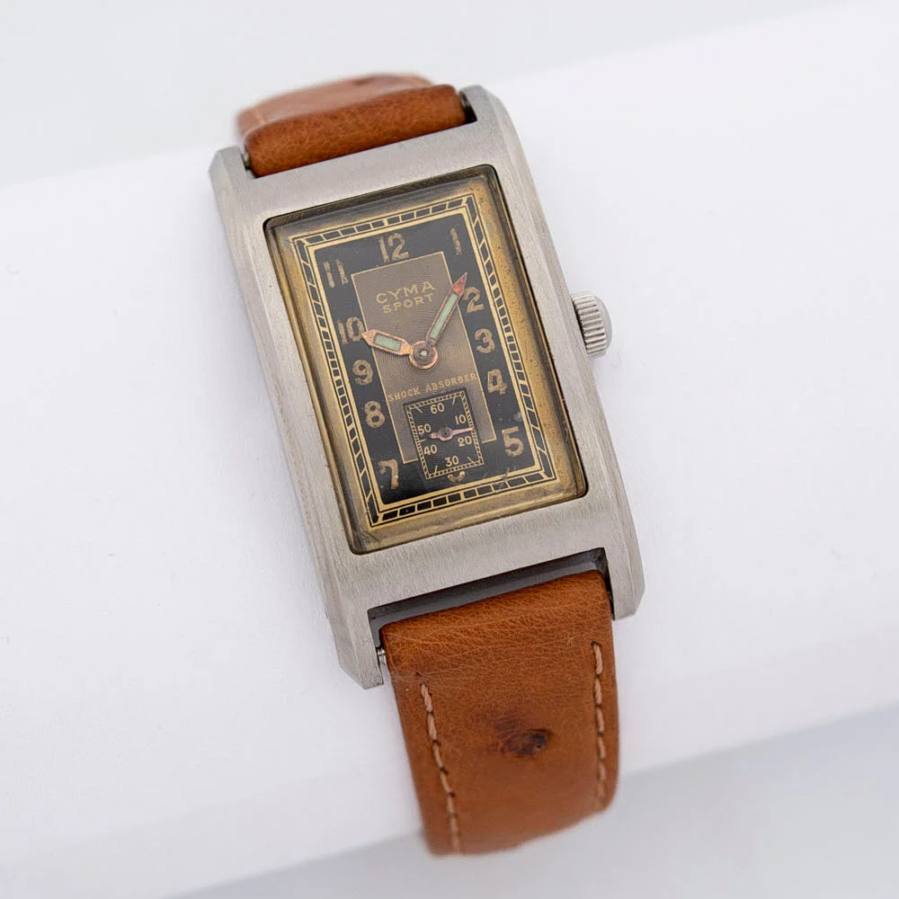 CYMA SPORT, ARMBANDUHR MIT HANDAUFZUG, SEKUNDENZEIGER BEI 6 UHR, ZWEIFARBIGES ZIFFERBLATT IN GOLD UND SCHWARZ, WASSERDICHTES DELSTAHL GEHÄUSE, UM 1930ER JAHRE. — Wristwatches — Kunst- und Auktionshaus Kleinhenz