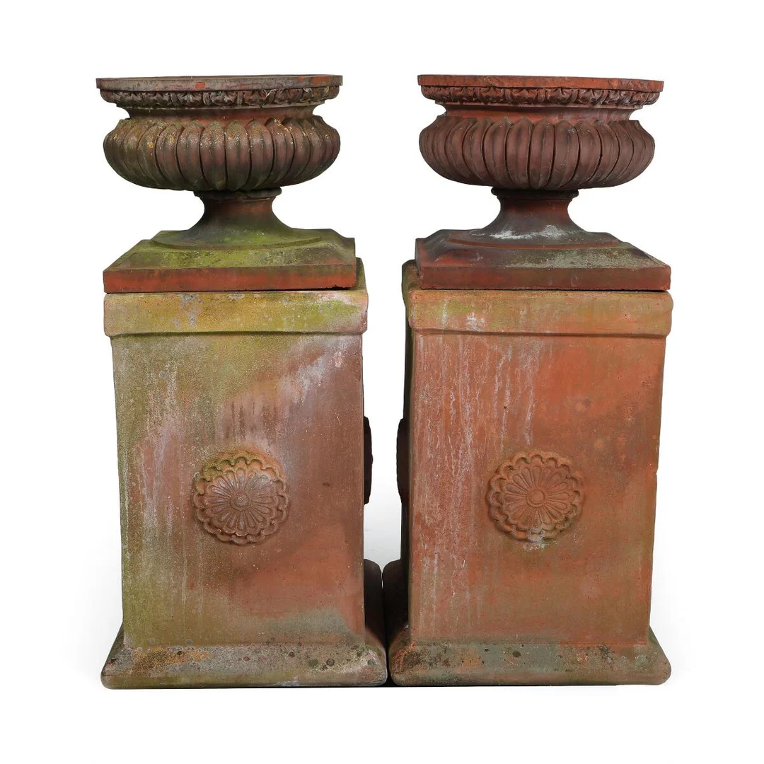 A pair of terracotta garden urns with fluting. Mounted on four-sided pedestals. 20th century. Combined H. 94 cm. (4) — Antique Furniture — Bruun Rasmussen