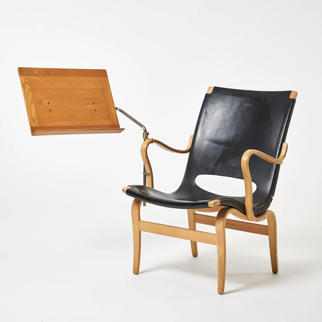 BRUNO MATHSSON. "Eva", fåtölj med läsplatta, Firma Karl Mathsson, Värnamo stomme av skiktlimmat böjträ av bok, klädd i svart läder. — Armchairs & Chairs — Stockholms Auktionsverk Magasin 5