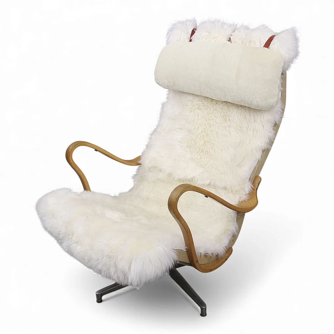 BRUNO MATHSSON. Fåtölj på snurrfot, "Pernilla", med fårskinnsklädsel, benställning av bok. — Armchairs & Chairs — Limhamns Auktionsbyrå