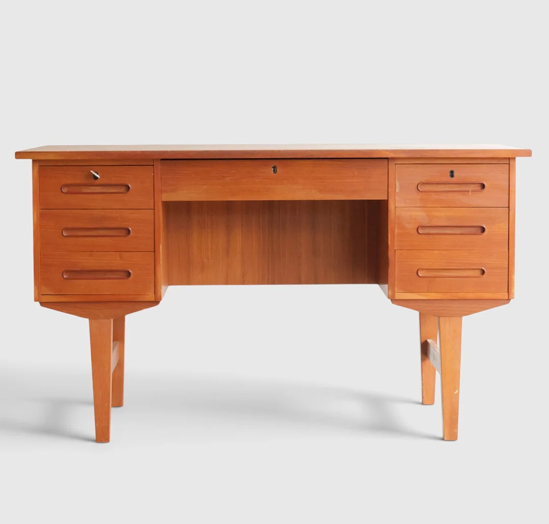 Fritstående skrivebord af teak, front med syv skuffer, bagside med hylde, bagside med hylde. Danmark, 1960'erne. — Desks — Woxholt Auktionshus