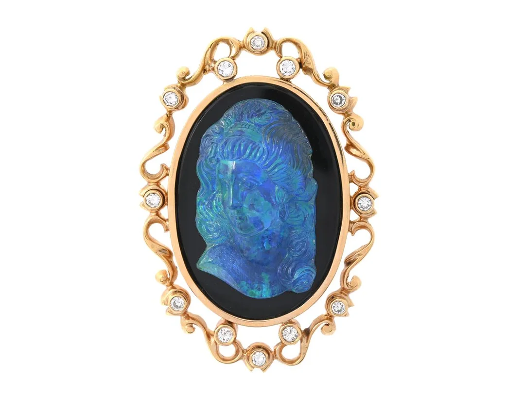 BROSCH, 18K guld, snidad opaltriplett, onyx, 12 briljantslipade diamanter ca 0,35 ctv, ca TW-TCr/SI, Bengt Anderssons Guld, Stockholm, mått 45 x 32 mm, vikt 16,1 g, några diamanter med nagg. — Smycken/Brosch — Kaplans