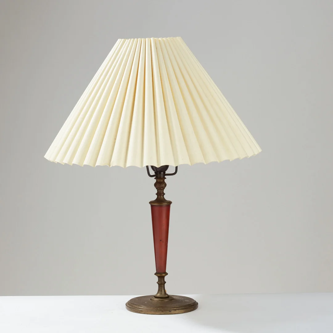 ERIK TIDSTRAND (1876–1944). Table lamp of patinated brass or bronze with a conical stem clad in dark red Pollopas, model no. 26551, Nordiska Kompaniet, Sweden, 1920s. — Table Lamps — Palsgaard Kunstauktioner