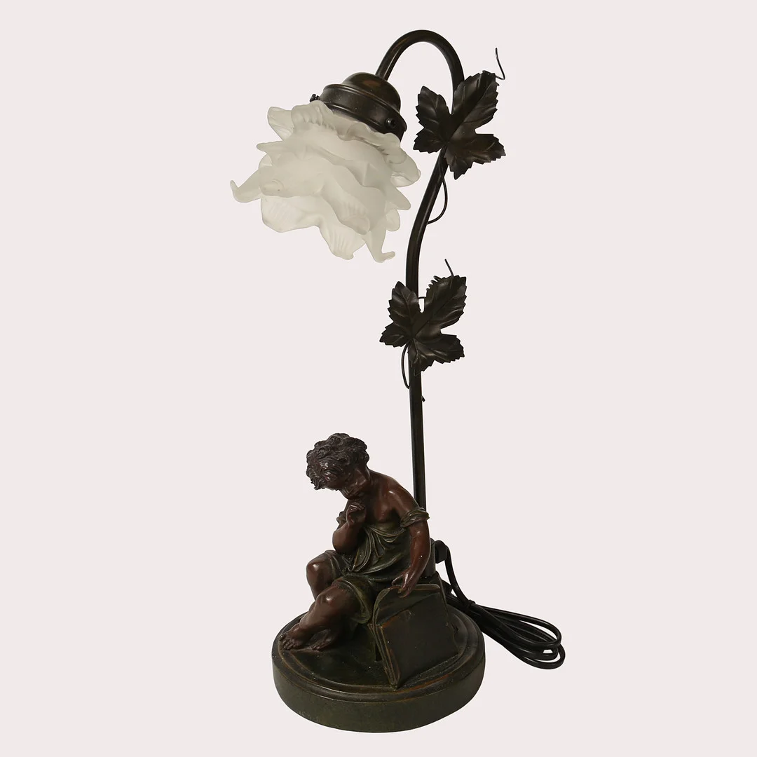 BORDSLAMPA, i form av ett sittande barn med portfölj, efter Moreau, Frankrike, senare tillverkning. — Table Lamps — Limhamns Auktionsbyrå