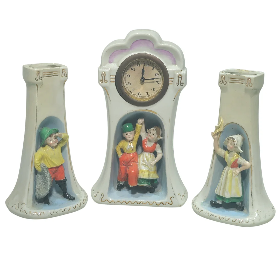 Reloj de sobremesa en porcelana con guarnición de violeteros con figuras. Finales siglo XIX-principios siglo XX. — Mantel clocks — Arce Auctions