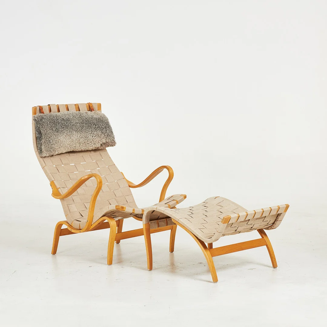 BRUNO MATHSSON. Fåtölj med fotpall, "Pernilla", för DUX, stomme i björk, klädd i sadelgjord canvastyg, nackudde i fårskinn, brännmärkta. — Armchairs & Chairs — Stockholms Auktionsverk Sickla