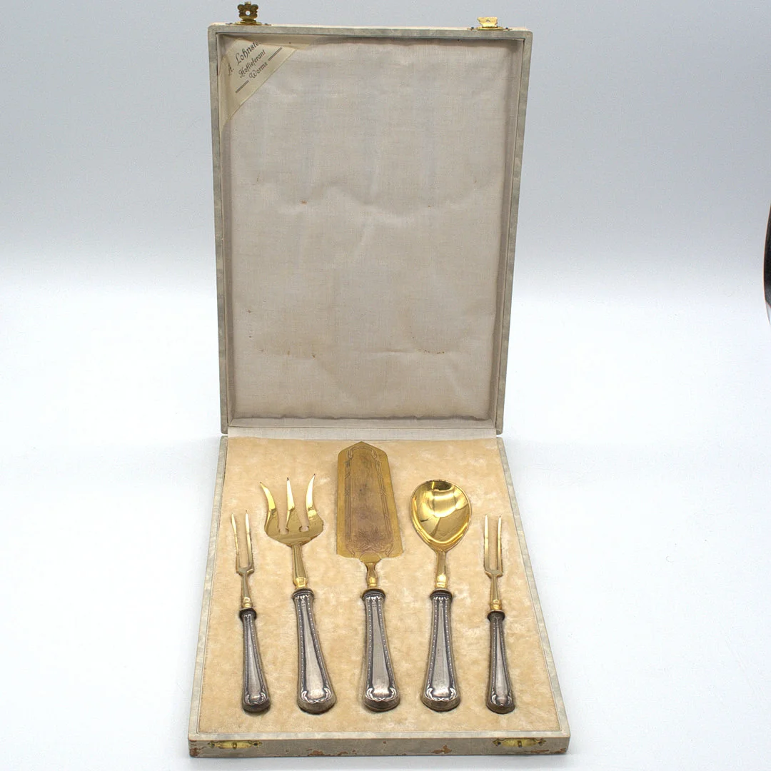 A. LOHNSTEIN. WORMS, HOFLIEFERANT, ANTIKES VORLEGEBESTECK, GRIFFE AUS 800ER SILBER, ZINKEN AUS VERGOLDETEM MESSING, IM ORIGINAL KASTEN UM 1900. — Silver — Kunst- und Auktionshaus Kleinhenz