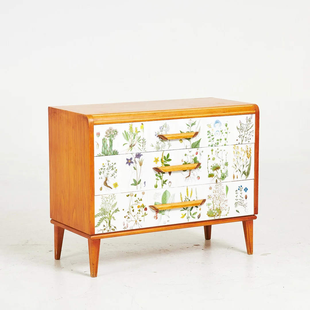 BYRÅ, 1940/50-tal, tre utdragslådor, lådfronter senare tapetserad med Nordens Flora. — Chests of drawers — Stockholms Auktionsverk Sickla