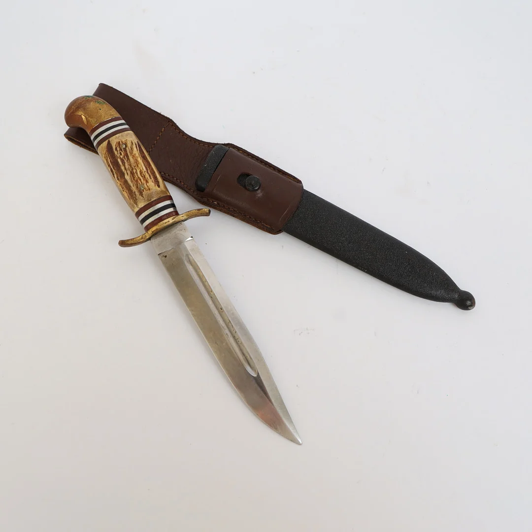 ERIK FROST. Handtag av horn med inläggningar, blad av stål, slida av läder och svärtad metall. — Edged weapons — Falun Auktionsbyrå