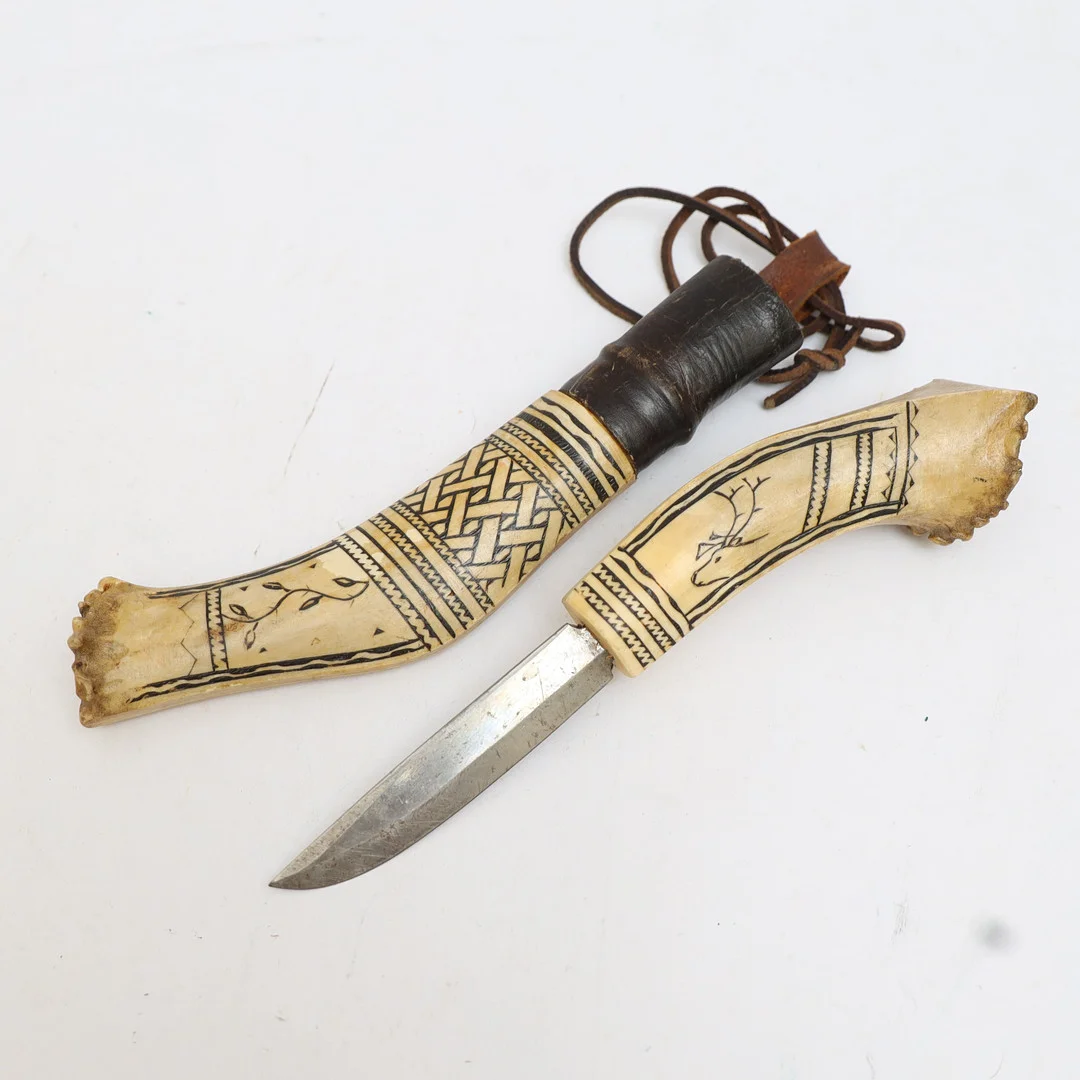 KNIV MED SLIDA, Samearbete, Handtag och slida av horn med skuren och färgad deklor. Daterad 1947 Vålådalen. — Edged weapons — Falun Auktionsbyrå