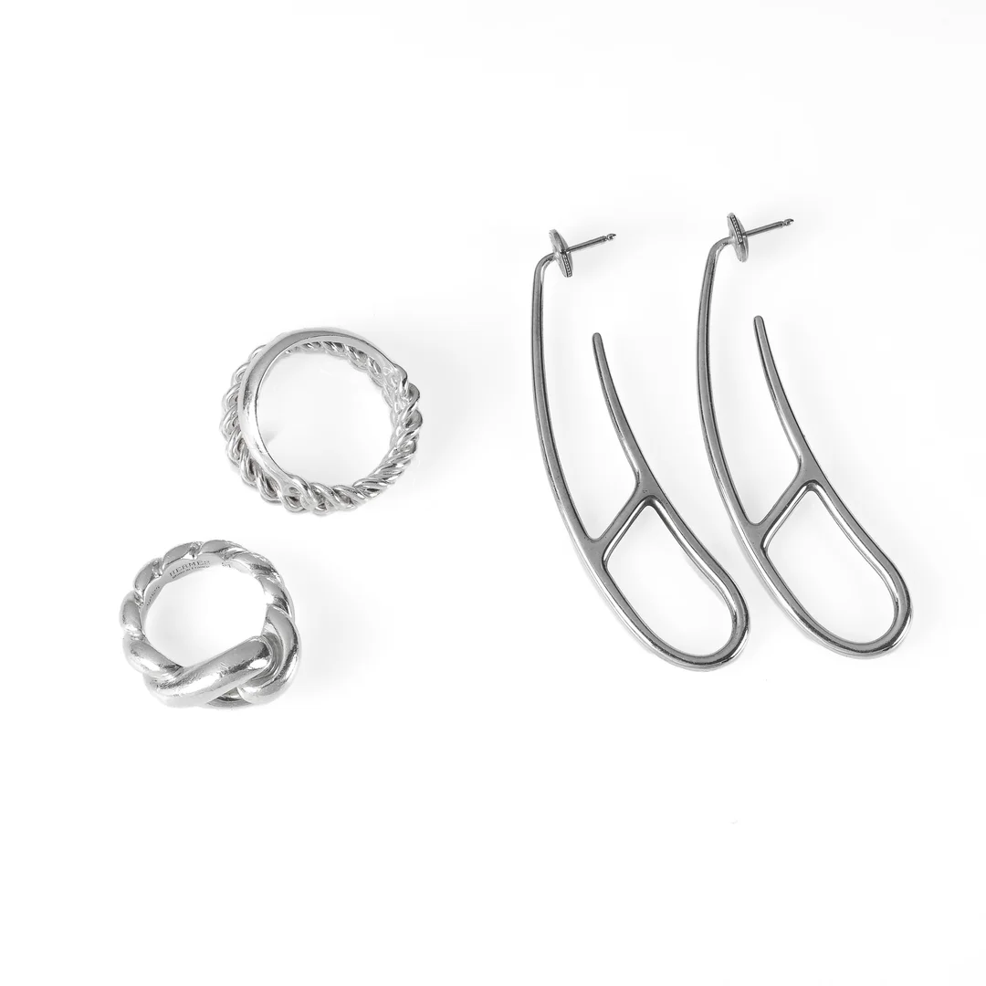 Hermés: A 'Boucle Sellier Inflexible' and a 'Torsade' ring and a pair of 'Chaine d'ancre Punk' ear pendants of sterling silver. (4) — Jewellery/Rings — Lauritz