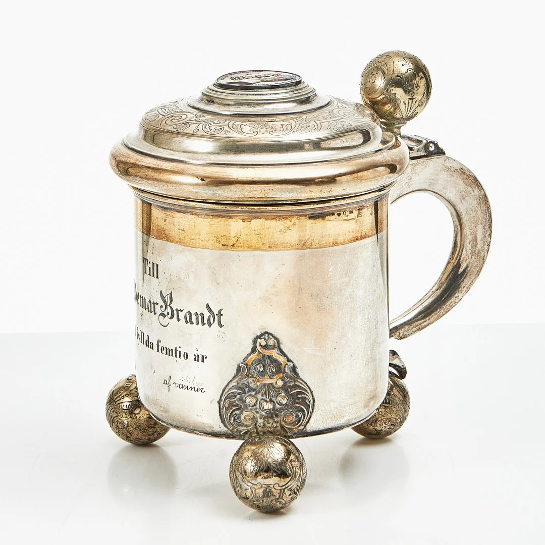 DRYCKESKANNA, silver, Axelsons GAB, Stockholm 1898, barockstil, cylinderformad, på tre kulfötter, ciselerad dekor, invändigt förgylld. — Silver — Stockholms Auktionsverk Magasin 5
