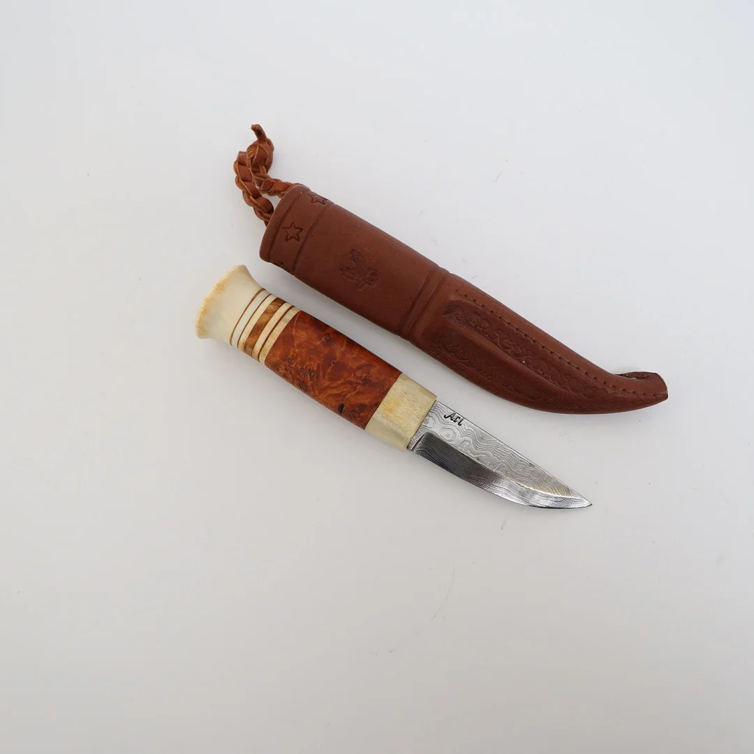 KNIV MED SLIDA, Handtag av horn och trä, damaskerat blad av stål, slida av läder. — Edged weapons — Falun Auktionsbyrå